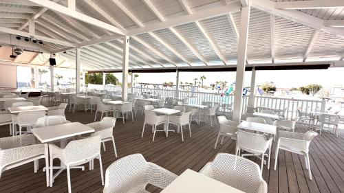 a restaurant with white tables and chairs on a deck at Caleta Dorada in Caleta De Fuste