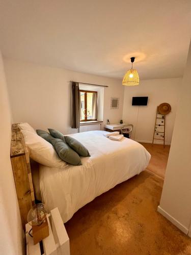 une chambre avec un grand lit blanc avec des oreillers dans l'établissement Gîte Brin de Nature au cœur de la nature bugiste, à Ambérieu-en-Bugey