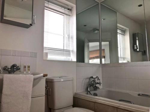 uma casa de banho com um WC, um lavatório e um espelho. em A 3 bedroom townhouse is located in the centre of Newbury em Newbury
