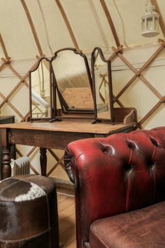 a room with a table with a mirror and a leather couch at Luxury Yurts in Michaelchurch Escley