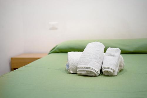 two rolled towels sitting on a green bed at Primo mare, borgo dei pescatori in Cervo