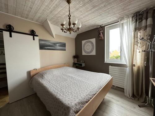 a bedroom with a bed and a window and a chandelier at Villa les Buissonets in Berck-sur-Mer