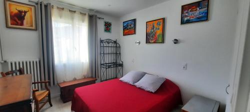 um quarto com uma cama vermelha e uma janela em gîte Aux Tourterelles em Tournemire