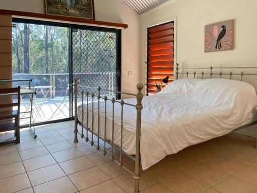 een slaapkamer met een bed en een groot raam bij Lush 2Bedroom Apartment in Yamba Hinterland in Ashby