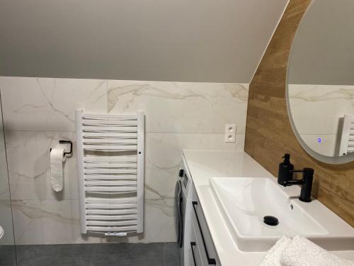 a white bathroom with a sink and a mirror at Apartamenty przy Parku Szwedzkim in Szczawno-Zdrój