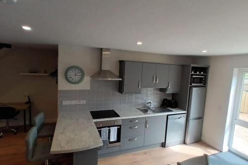 una cocina con electrodomésticos de acero inoxidable y un reloj en la pared en Stunning New 3 Bed Townhouse, en Belmullet