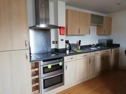 uma cozinha com armários de madeira e um forno com placa de fogão em Pelican House is an exclusive contemporary development em Newbury