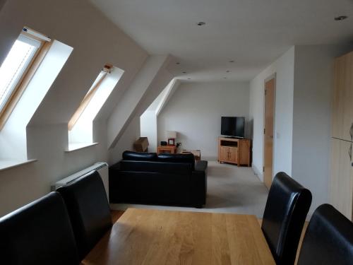 uma sala de estar com um sofá preto e uma televisão em Pelican House is an exclusive contemporary development em Newbury