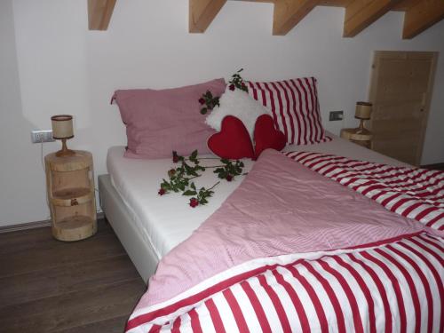 a bedroom with a bed with red and white sheets at Apartments Resi in Rasùn di Sotto