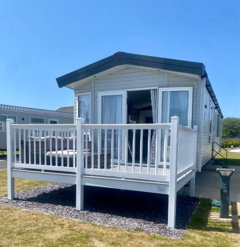a tiny house with a porch and a deck at Hafan Y Môr Caravan - Pwllheli in Chwilog