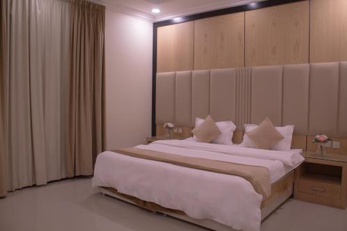 um quarto com uma cama grande com lençóis brancos e almofadas em منازل الريم (فرع العزيزية) em Riyadh