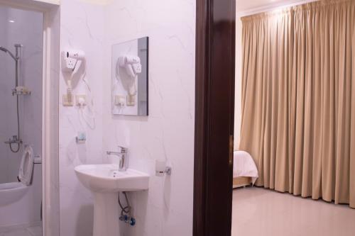 a white bathroom with a sink and a shower at منازل الريم للشقق المخدومة فرع العزيزية in Riyadh