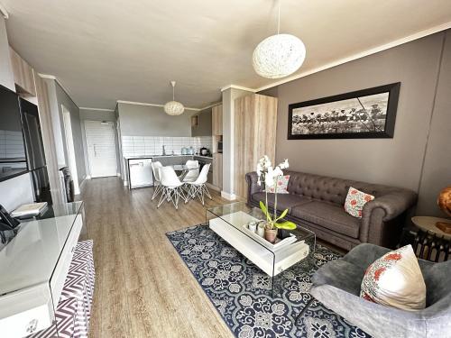 ein Wohnzimmer mit einem Sofa und einem Tisch in der Unterkunft WATERS EDGE 103 in Kapstadt