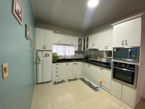 uma grande cozinha com armários brancos e um frigorífico em Casa Bignonia Amplio y confortable Ideal para familias con niños y mascotas em Ciudad del Este