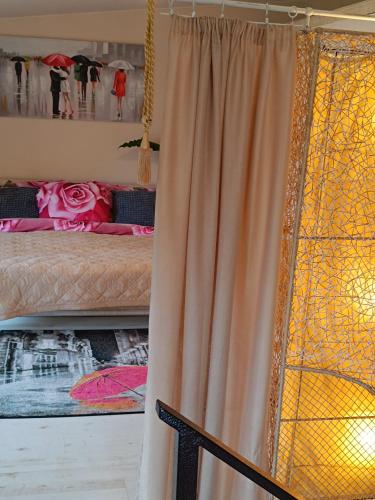 a bedroom with a bed with a curtain and a window at Namelis uždarame kieme in Šiauliai