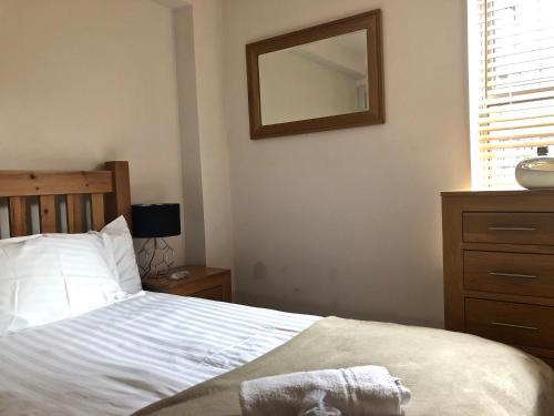 ein Schlafzimmer mit einem Bett mit einem Spiegel und einer Kommode in der Unterkunft Pelican House is an exclusive contemporary development in Newbury