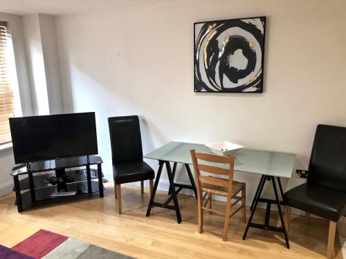 een woonkamer met een tafel en stoelen en een televisie bij Pelican House is an exclusive contemporary development in Newbury