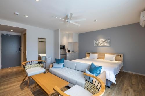 a bedroom with a bed and a couch and a table at ALPHABED Inn Naha Kokusai Street West in Tsuboya
