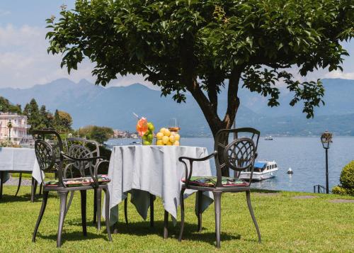 a table and chairs with a table and a tree at Hotel Villa e Palazzo Aminta in Stresa