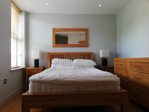 a bedroom with a bed with white sheets and a mirror at Pelican House is an exclusive contemporary development in Newbury