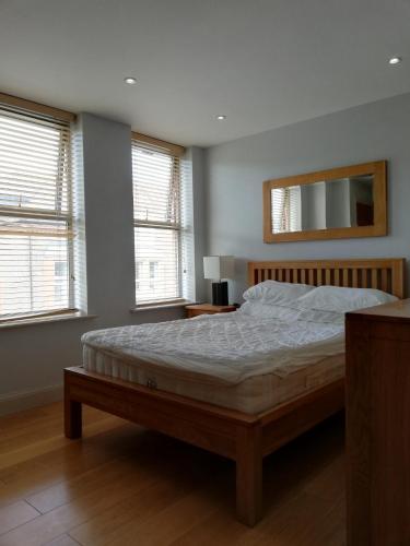 um quarto com uma cama, um espelho e janelas em Pelican House is an exclusive contemporary development em Newbury