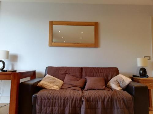 a brown couch in a living room with a mirror at Pelican House is an exclusive contemporary development in Newbury