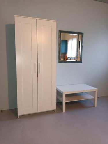 a white cabinet with a table and a mirror at Studio Bella in Ancient Epidauros