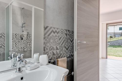 een badkamer met een wastafel, een douche en een spiegel bij Chalet La Greta - Casa vista campi in Firenzuola