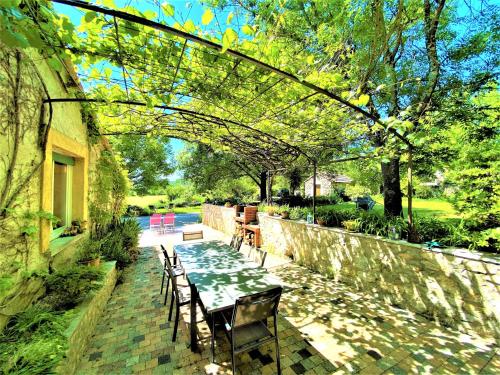 a patio with a table and chairs and a stone wall at Gîte de groupe 15 à 19p, parc, salle de réception - CHAMBRES D'HOTES en semaine in Villeneuve-de-Berg