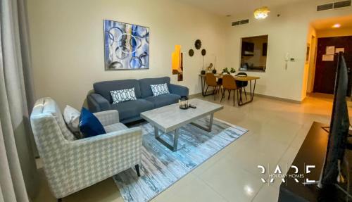 a living room with a blue couch and a table at Rare Holiday Homes presents Large 1 Bed in a peaceful community of JVC -La Riviera Estate B R106 in Dubai
