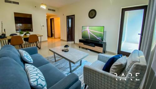 a living room with a blue couch and a tv at Rare Holiday Homes presents Large 1 Bed in a peaceful community of JVC -La Riviera Estate B R106 in Dubai