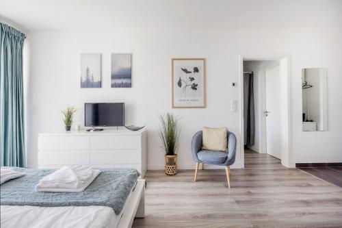 una camera bianca con un letto e una sedia di Modern Riverfront Apartment with Free Parking a Budapest