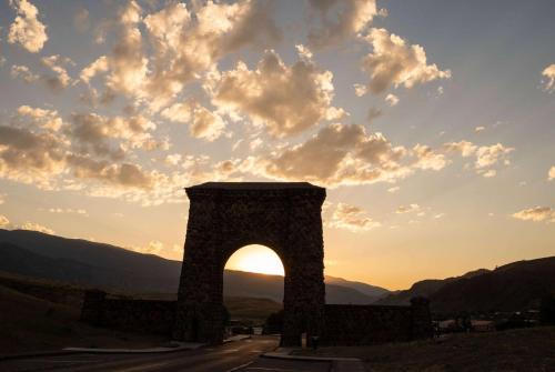 an arch in the middle of a road with the sunset at Super 8 by Wyndham Gardiner/Yellowstone Park Area in Gardiner