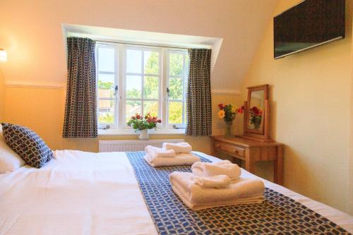 a bedroom with towels on a bed with a window at Bumble Bee Cottage in Burley