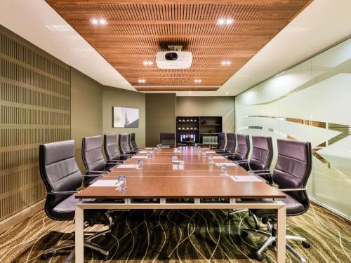 a conference room with a long table and chairs at Novotel Christchurch Cathedral Square in Christchurch