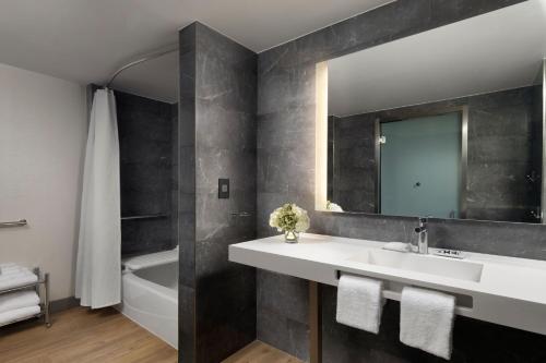 a bathroom with a sink and a mirror and a tub at AC Hotel by Marriott Pleasanton in Pleasanton