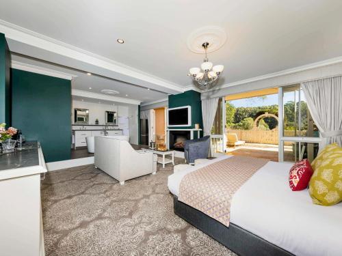 a bedroom with a bed and a living room at Grand Mercure Basildene Manor in Margaret River Town