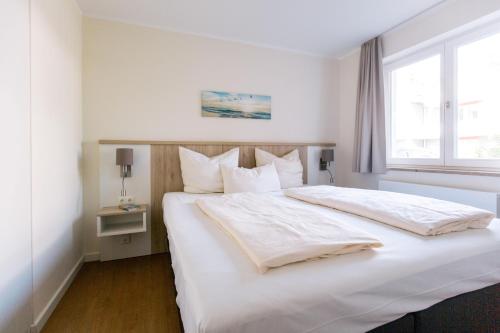 a bedroom with a large white bed with a window at Panorama_Apartment 1 P6 optional P in Plau am See