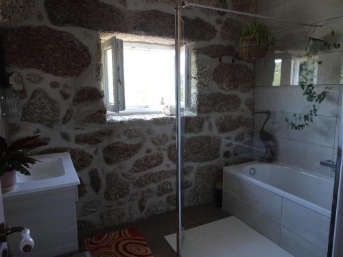 baño con ducha y bañera y ventana en A CASA COM 2 PEREIRAS en Terras de Bouro