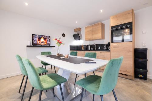 a kitchen and dining room with a white table and green chairs at Haus Paul in Kals am Großglockner