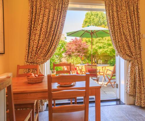 a dining room with a table and an umbrella at Bumble Bee Cottage in Burley