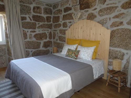 a bedroom with a large bed with a stone wall at A CASA COM 2 PEREIRAS in Terras de Bouro