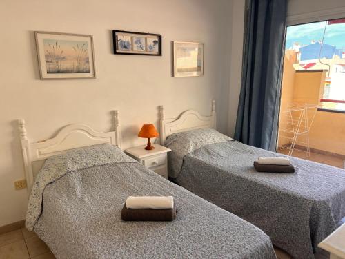 Dos camas individuales en una habitación con ventana. en Jardín, en Puerto de Santiago