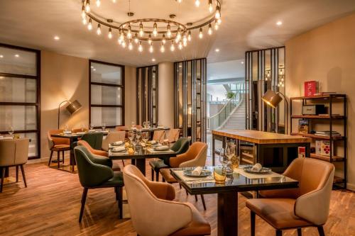 a restaurant with tables and chairs and a chandelier at Munich Marriott Hotel in Munich