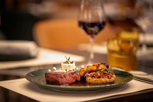 a plate of food on a table with a glass of wine at Munich Marriott Hotel in Munich