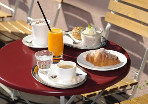 a red table with two plates of food and cups of coffee at Hotel Stoller in Zürich