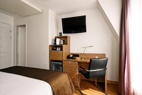 a bedroom with a bed and a desk with a television at Hotel Stoller in Zürich