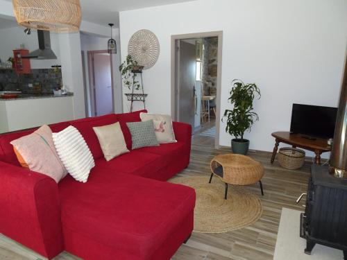 a living room with a red couch and a table at A CASA COM 2 PEREIRAS in Terras de Bouro