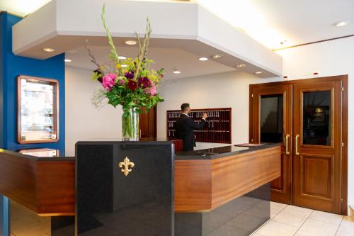 a man standing at a reception desk in a lobby at Hotel Stoller in Zürich