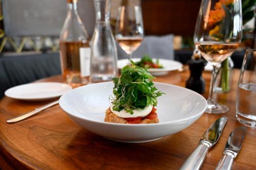 a white bowl of food on a table with wine glasses at Hotel Stoller in Zürich
